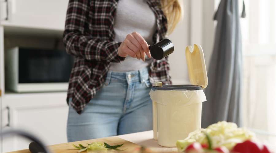 photo d'une femme utilisant un composteur bokashi dans sa cuisine.