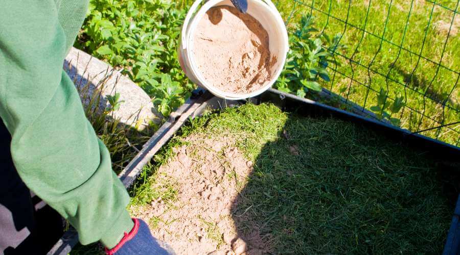 photo en gros plan d'une personne utilisant un activateur de compost en poudre