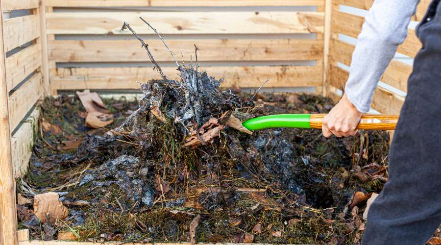 Photographie d'une personne réalisant un brassage de son compost à l'aide d'une fourche.